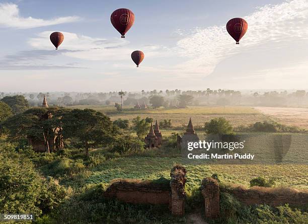 hot air balloons flying over ancient temples - bagan photos et images de collection