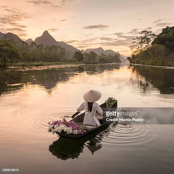 woman rowing boat along river, carrying flowers - vietnam photos et images de collection