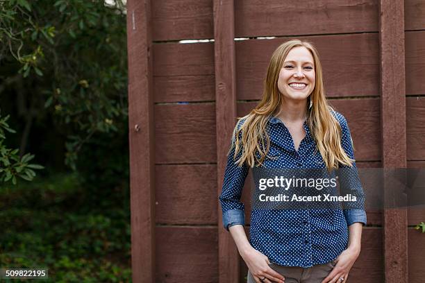 woman relaxes against shed door, forest home - shed stock-fotos und bilder