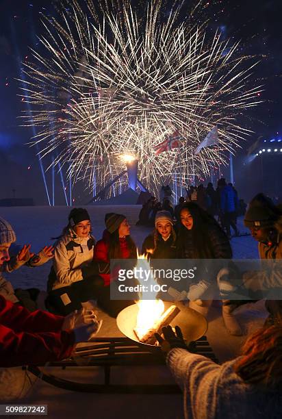 In this handout image supplied by the IOC, Performers sit around a fire as fireworks explod over Lysgrdsbakkene Ski Jumping Arena during the Opening...