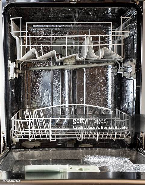 interior of a dishwasher opened in functioning throwing water jets - pastille pour lave vaisselle photos et images de collection