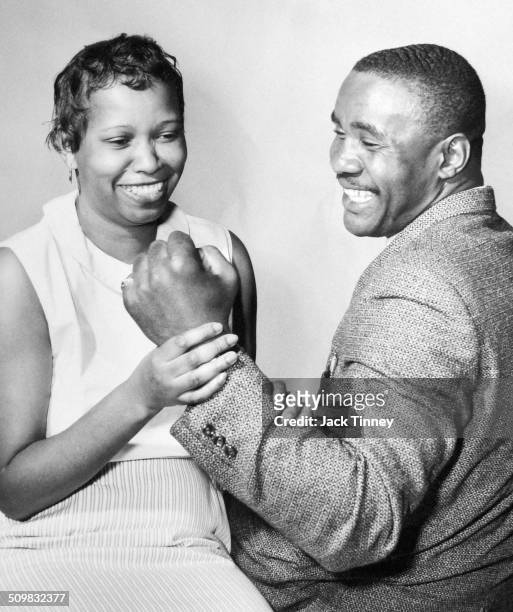 American heavyweight boxer Sonny Liston smiles as his wife, Geraldine , holds his clenched fist, 1969.