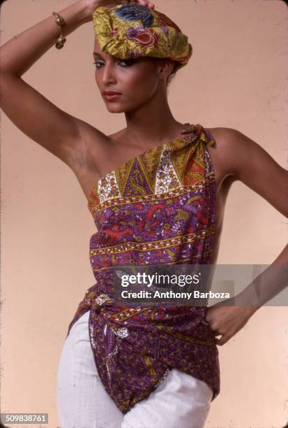 Portrait of model Sheila Johnson dressed in a print top and matching fabric headpiece, New York, 1970s.