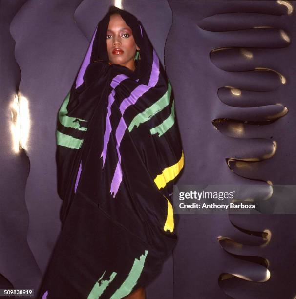 Portrait of American fashion model Toukie Smith as she poses wrapped in a dark multi-colored robe, New York, New York, early 1980s.