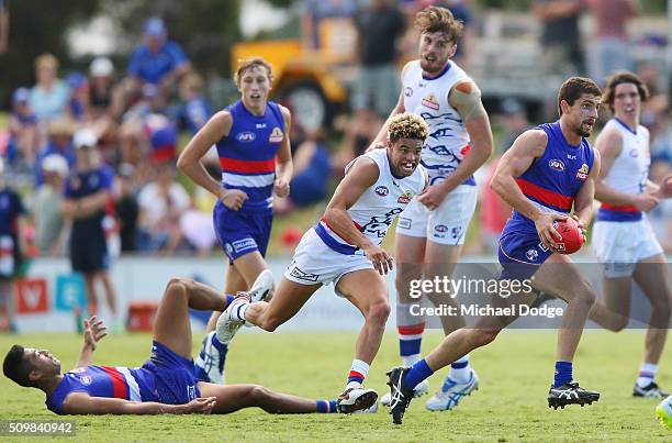 Tom Liberatore of the Bulldogs, making his comeback from a knee reconstuction, runs with the ball away from Jason Johannisen of the Bulldogs during...