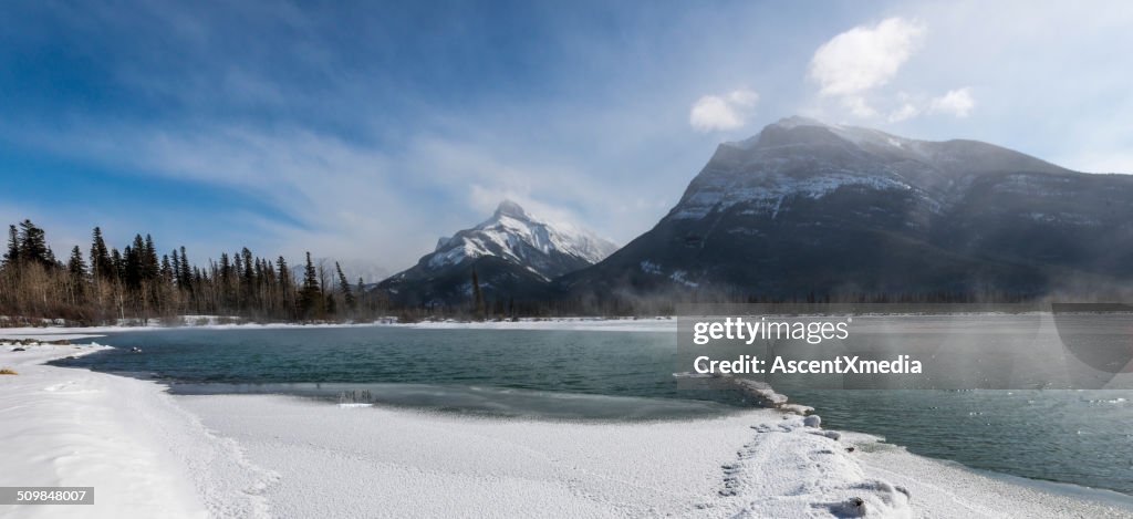 Steam rises from mountain lake in early winter