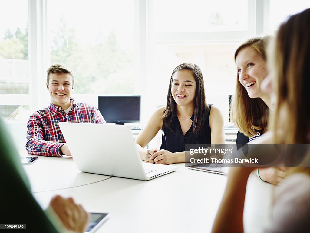 Students at desk in classroom listening to teacher