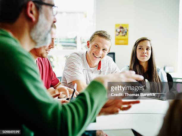 smiling students listening to teacher lecture - lehrer schüler stock-fotos und bilder