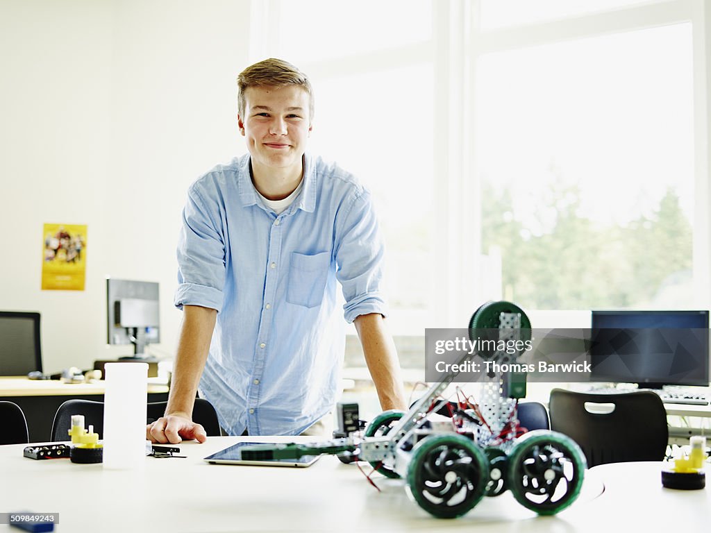 Smiling male student in classroom with robot