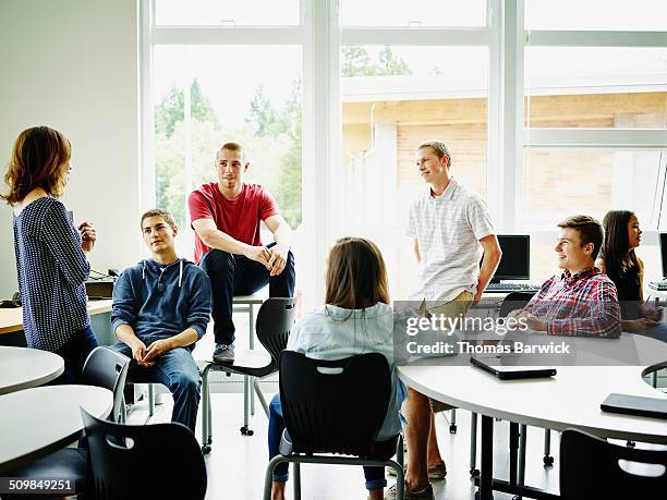 female teacher in class discussion with students - boy and girl talking stock-fotos und bilder