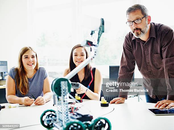 male teacher helping female students operate robot - wonderlust computer stock pictures, royalty-free photos & images