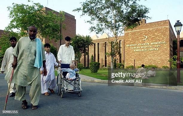 Pakistani people walk infront of the entrance to the Shaukat Khanum Memorial Cancer Hospital and Research Centre, founded by former Pakistani cricket...