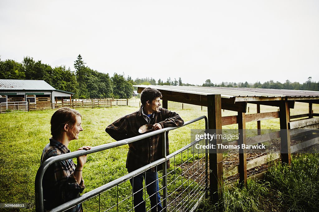 Smiling young farmers looking out at pasture