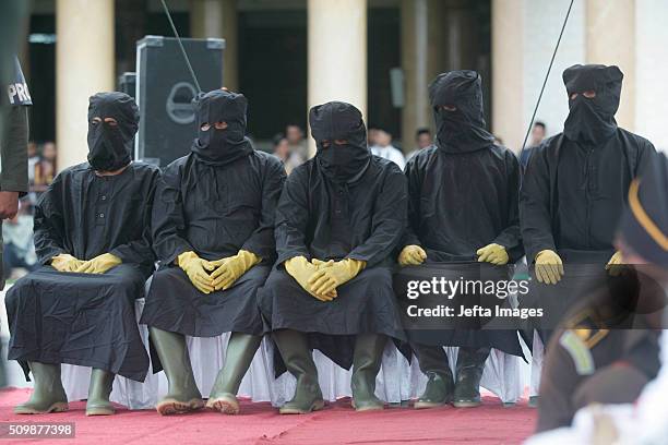 Punishers, locally known as 'algojo' wait to whip the alleged sharia law offenders during the whipping punishment in front of public at Meulaboh on...