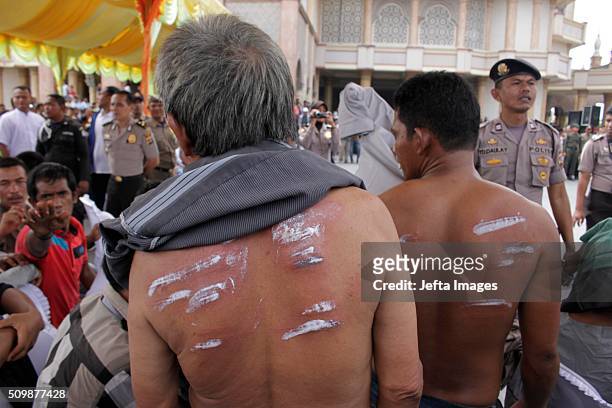 The injureies of a whipped person are treated with salve during the whipping punishment in front of public at Meulaboh on February 12, 2016 in West...