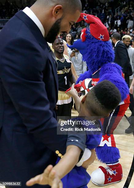 Canada coach Drake holds back a small child who continues to give it to USA coach/player Kevin Hart. The two had a play tussle on the court following...