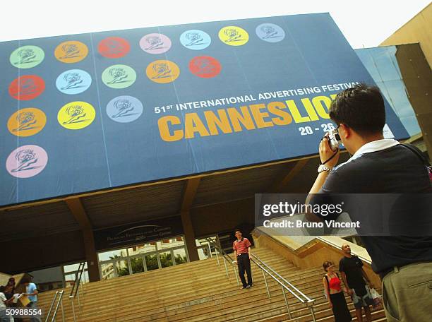 Tourist takes a photograph of the Palais des Festival entrance at the Cannes Lions International Advertising Festival on June 19, 2004 in Cannes,...