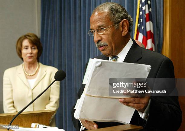 Rep. John Conyers holds a stack of recently released documents on the Abu Ghraib prison during a news conference with House Democratic Leader Nancy...