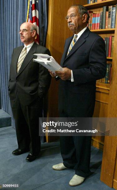 Rep. John Conyers holds a stack of recently released documents on the Abu Ghraib prison during a news conference with Rep. Henry Waxman on Capitol...