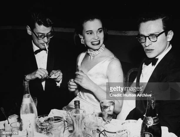 American photographer Richard Avedon , American heiress and designer Gloria Vanderbilt, and American film director Sidney Lumet, sit at a table...