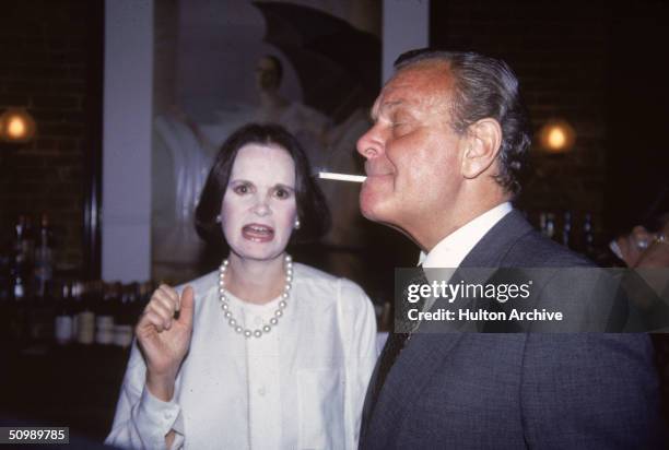 American heiress and designer Gloria Vanderbilt talks to American fashion designer Bill Blass as he smokes a cigarette at the bar at Mortimer's for a...