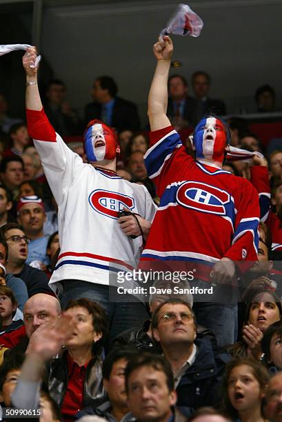 Two male fans of the Montreal Canadiens cheer for their team with their faces painted in team colors during game three of the eastern conference...