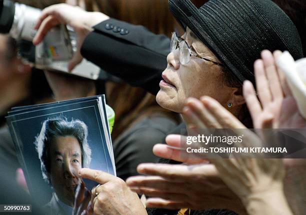 Holding leaflets of Japanese Prime Minister and ruling Liberal Democratic Party leader Junichiro Koizumi, a supporter of LDP listens to Koizumi's...