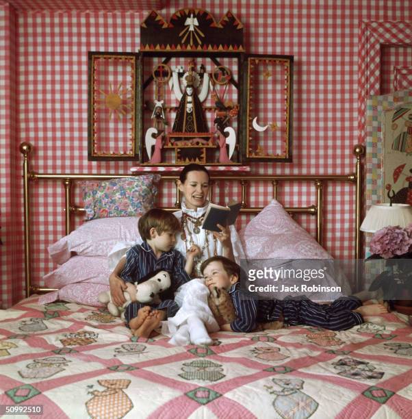 American heiress and socialite Gloria Vanderbilt reads to her two sons, Carter and Anderson, on a bed in their home, Southampton, Long Island, New...