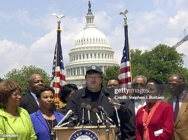 Filmmaker Michael Moore is surrounded by Congressional Black Caucus members as he speaks during a news conference June 24, 2004 on Capitol Hill in...