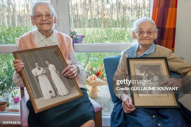 Centenary twins, Paulette Olivier and Simone Thiot pose with an old picture of their 20 years inside their room at the retirement home "Les Bois...