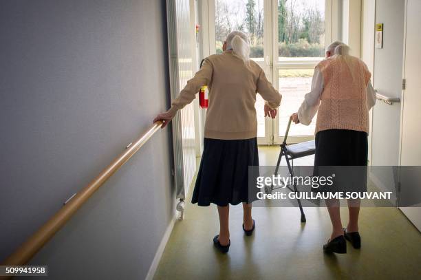 Centenary twins, Paulette Olivier and Simone Thiot walk in the corridors at the retirement home "Les Bois Blancs" on February 11, 2016.. The twins,...
