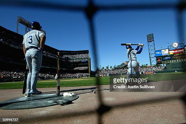 Cesar Izturis of the Los Angeles Dodgers looks on as teammate Dave Roberts warms up before the start of the game against the San Francisco Giants...