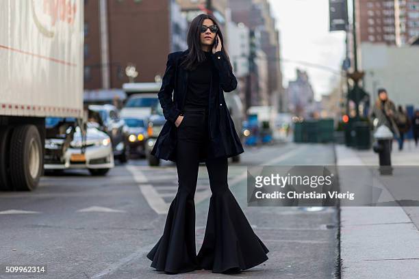 Fashion blogger Lainy Hedaya of Haute Inhabit wearing a A Moi black jacket, black Ellery flared pants, black Chanel sunglasses, a black Jimmy Choo...