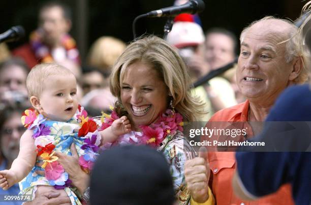 Show host Katie Couric holds a baby between songs with Jimmy Buffett live on NBC's "Today" show in Rockefeller Plaza June 25, 2004 in New York City.