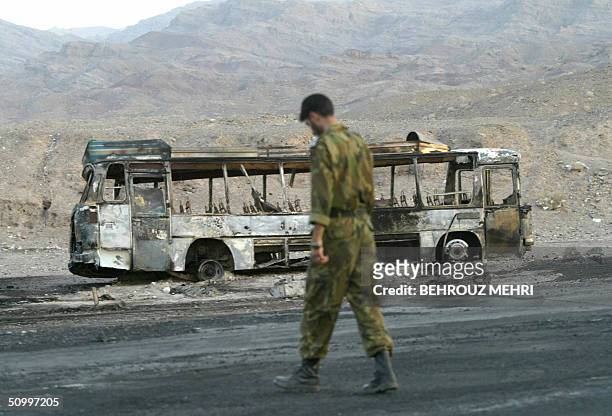 An Iranian soldier passes a burnt bus at the Nosrat Abad polic post, 115km west of the southeastern border town of Zahedan, 25 June 2004. At least 90...