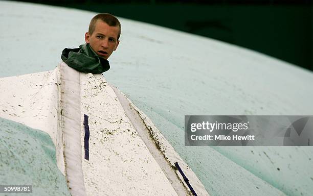 Grounds keeper removes the court cover during a rain delay at the Wimbledon Lawn Tennis Championship on June 26, 2004 at the All England Lawn Tennis...