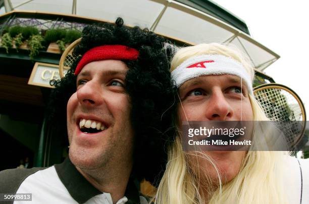 Fans, dressed as former Wimbledon tennis champions John McEnroe and Bjorn Borg, pose for a picture as they wait for play to start during a rain delay...