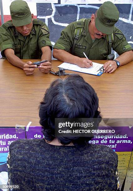 Una mujer entrega dos armas de fuego a miembros del Ejercito mexicano en Ciudad de Mexico el 26 de junio de 2004. El gobierno de la capital mexicana...