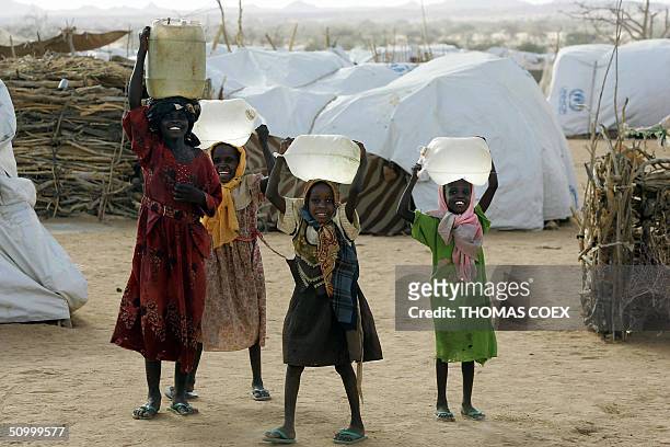Sudanese refugees carry water 26 June 2004 in Chad at the Iridimi refugee camp harbouring 15,000 refugees who fled the Darfur region where rebels...