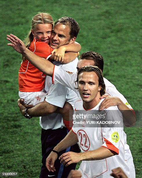 Dutch midfielder Boudewijn Zenden celebrates next to defender Frank De Boer holdin his daughter, 26 June 2004 at the Algarve stadium in Faro, at the...