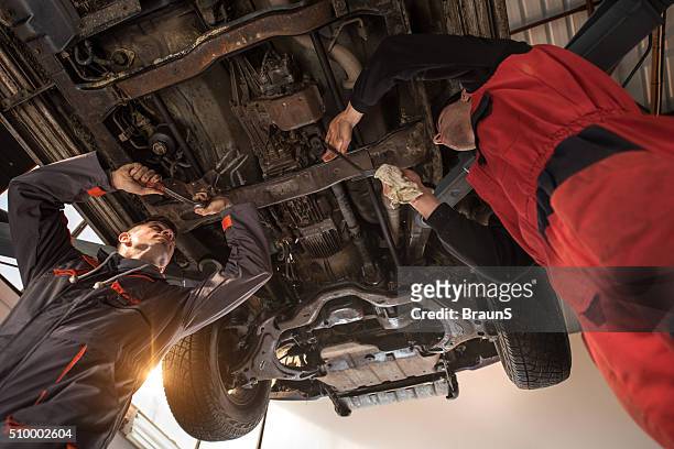 ein blick auf zwei mechaniker reparieren auto. - fahrgestell stock-fotos und bilder