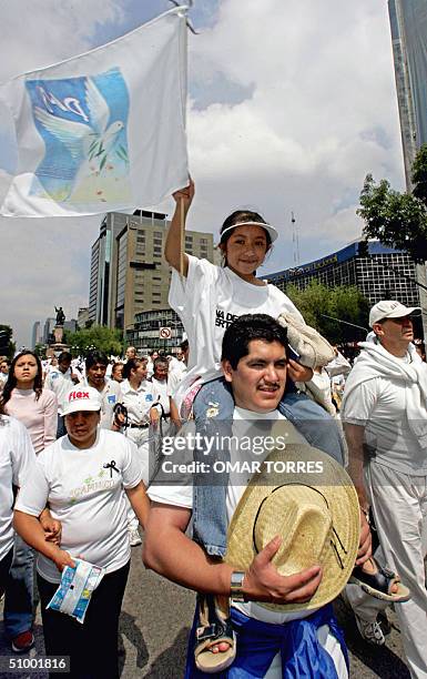 Una nina, llevada en los hombros de su padre, ondea una bandera con una paloma de la paz el 27 de junio de 2004 en una multitudinaria marcha por la...