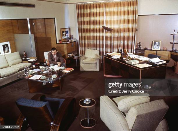 American movie producer, artist, and animator Walt Disney sits at a coffee table in his executive office, Hollywood, California, 1944.