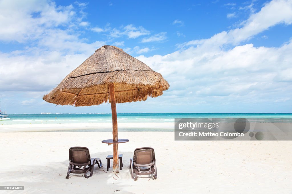 Sunshade and lounge chairs on sandy beach in the Caribbean