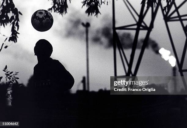 Young footballer involved with Inter Campus Project juggles a ball in front of an oil refinery April 15, 2002 in Abadan, Iran. Inter Campus is a...