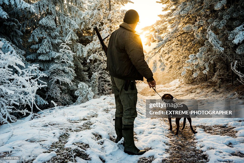 Hunter with dog in the snowy forest