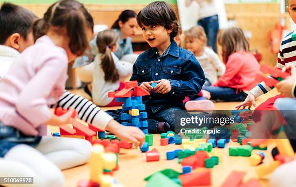 group of children playing with blocks in kindergarten. - peuterschool gebouw stockfoto's en -beelden