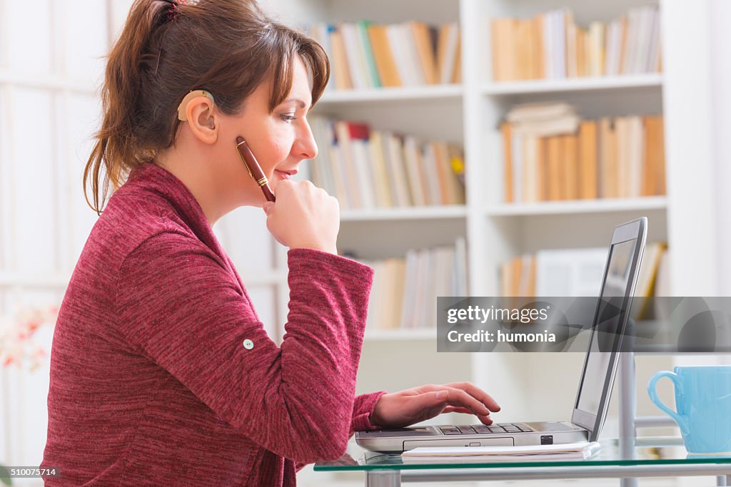 Hearing impaired woman working with laptop