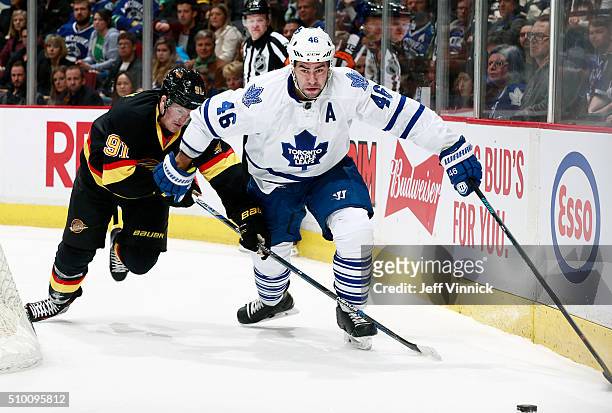 Jared McCann of the Vancouver Canucks pursues Roman Polak of the Toronto Maple Leafs during their NHL game at Rogers Arena February 13, 2016 in...