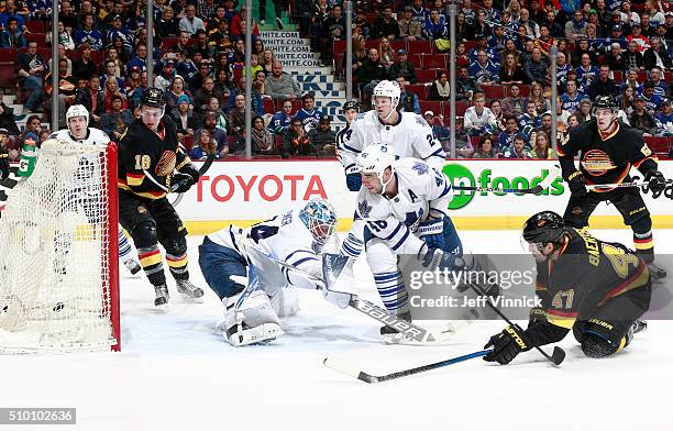 Sven Baertschi of the Vancouver Canucks scores on James Reimer of the Toronto Maple Leafs as he is checked by Roman Polak of the Maple Leafs during...